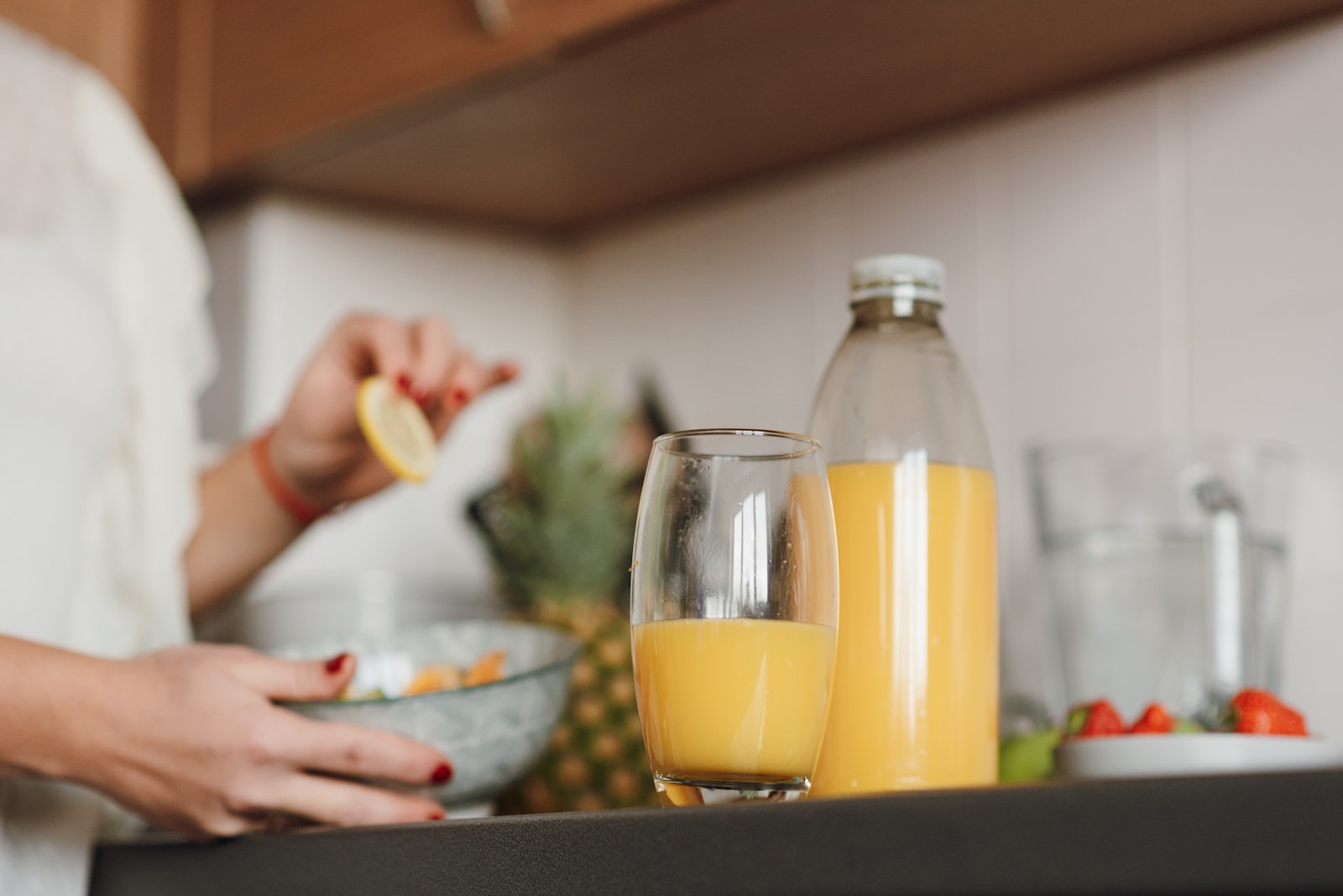 Crop woman cooking fruit salad in kitchen