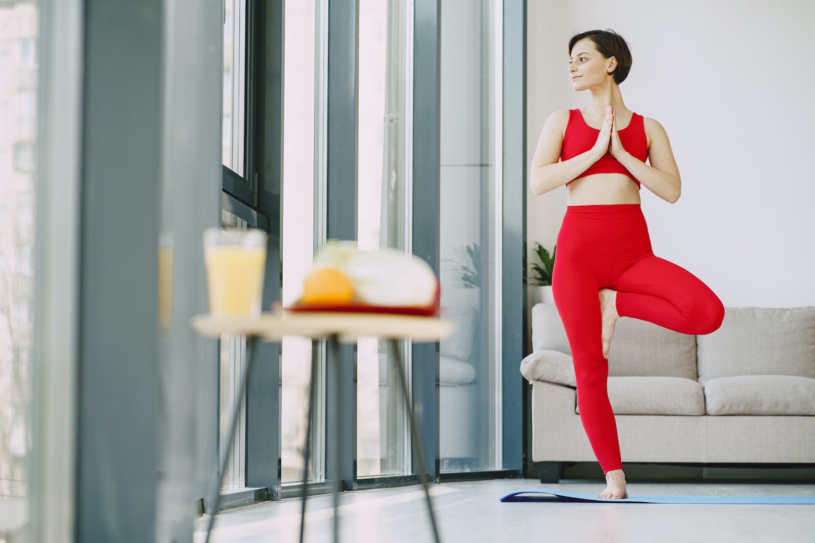 female in activewear standing on mat in living room while doing yoga