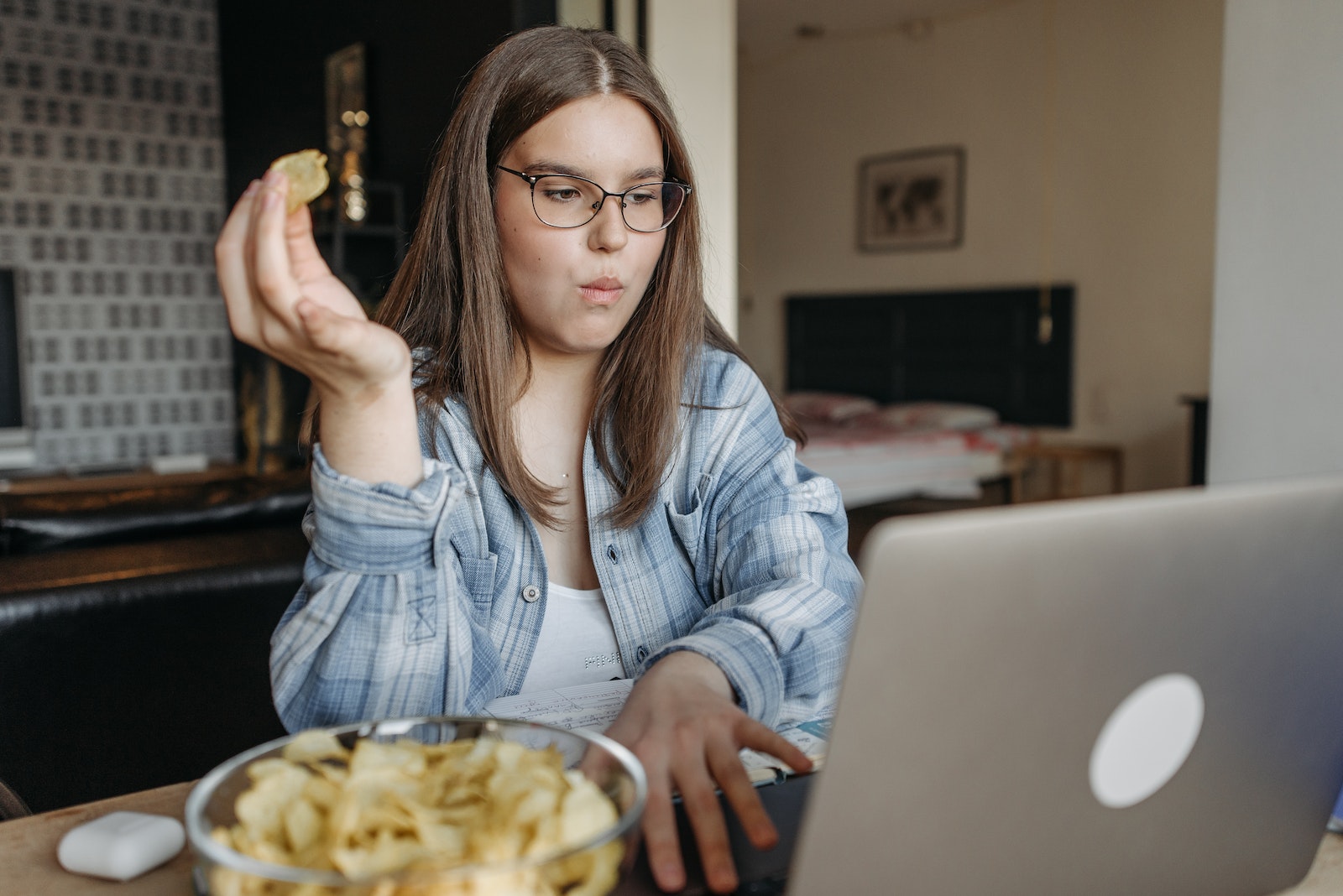 Woman Eating Chips while Using a Laptop