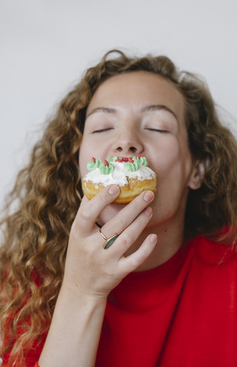 woman with long curly hair eating cupcake