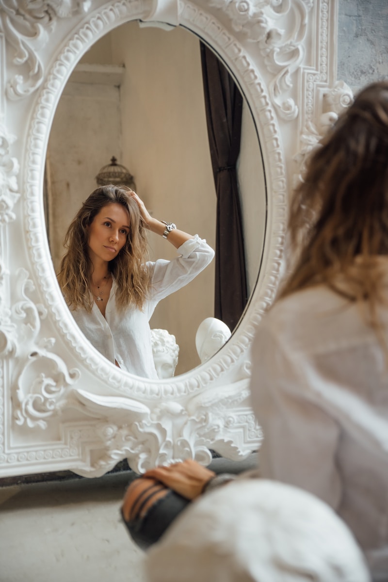 woman looking in mirror holding her head