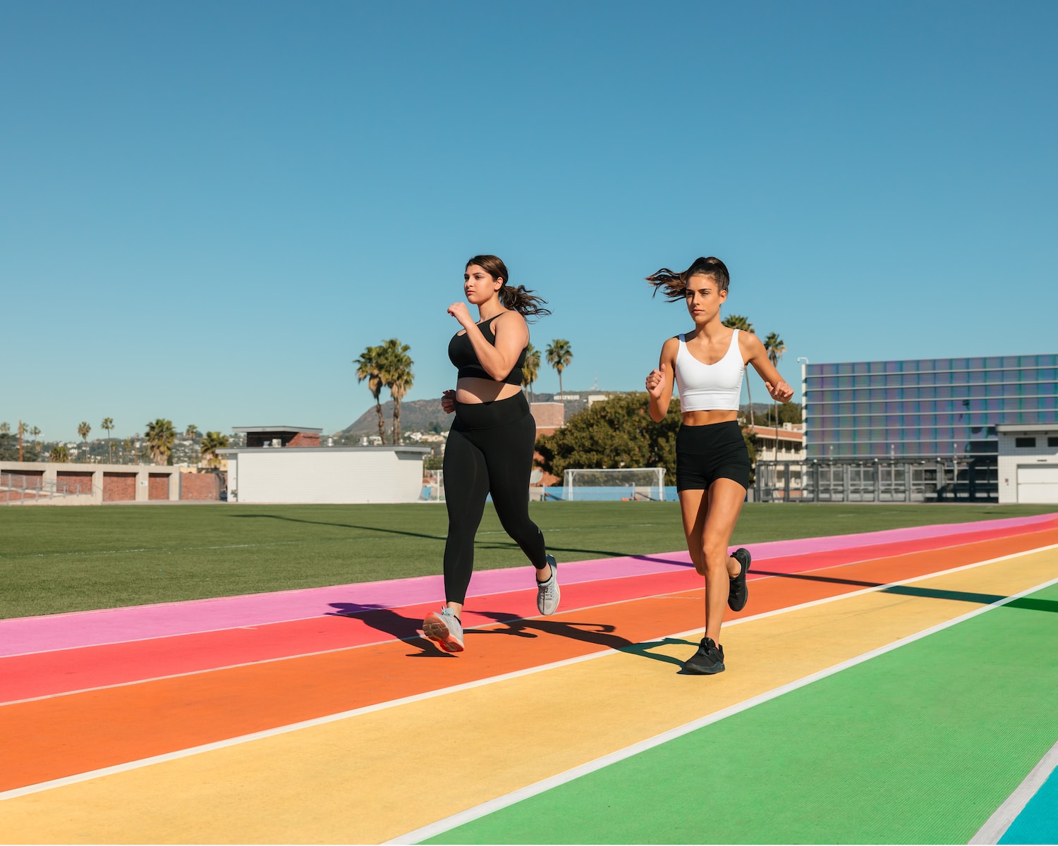 two women running on a rainbow colored track