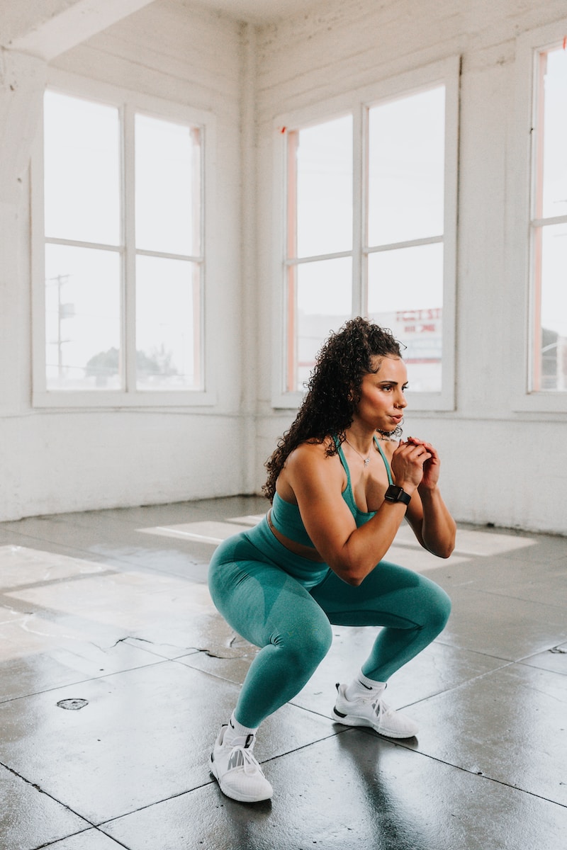 a woman squatting on the floor in a gym